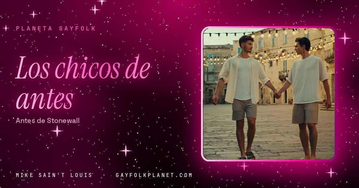Fotograma del videoclip de «Boys from the Village», de Mike Sain't Louis: dos chicos con camiseta blanca caminan de la mano por la plaza empedrada de un pueblo bajo guirnaldas de bombillas, en la portada de «Los chicos de antes»
