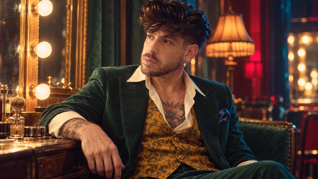 Mike Sain't Louis con americana de terciopelo verde y chaleco dorado en un camerino con espejo de bombillas — foto retro PLANETA GAYFOLK.