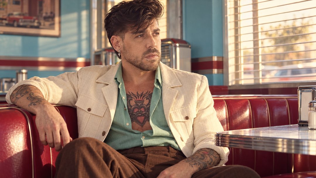 Mike Sain't Louis con americana crema y camisa verde en el reservado rojo de un diner — foto retro PLANETA GAYFOLK.