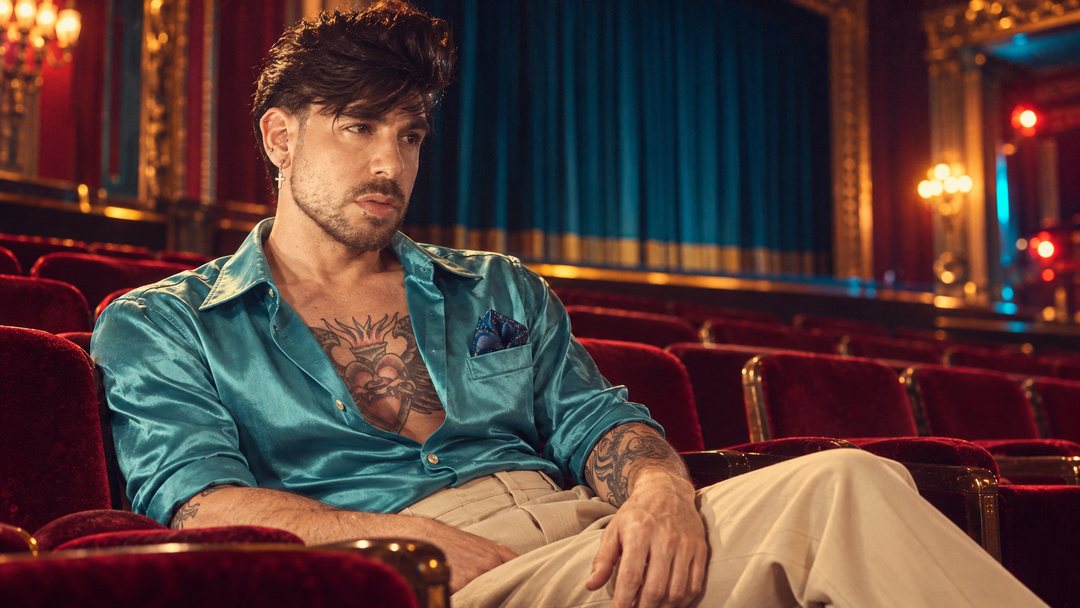 Mike Sain't Louis con camisa satinada turquesa recostado en las butacas rojas de un teatro — foto retro PLANETA GAYFOLK.