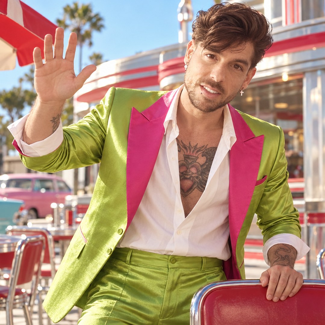 Mike Sain't Louis saludando con traje verde lima de solapas fucsia en la terraza de una cafetería retro — foto PLANETA GAYFOLK.