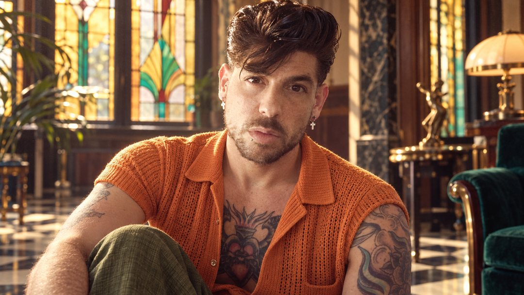 Mike Sain't Louis con camisa naranja de punto en un salón con vidrieras de colores — foto retro PLANETA GAYFOLK.